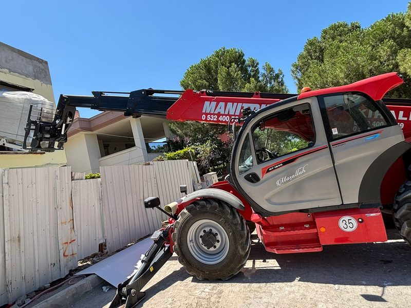 Fabrika ve depo operasyonunda paletli yükü taşıyan Manitou teleskopik yükleyici
