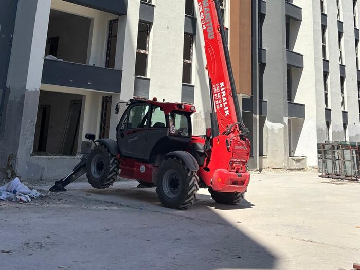 Yüksek katlı bina inşaatının önünde konumlanmış Manitou teleskopik yükleyici